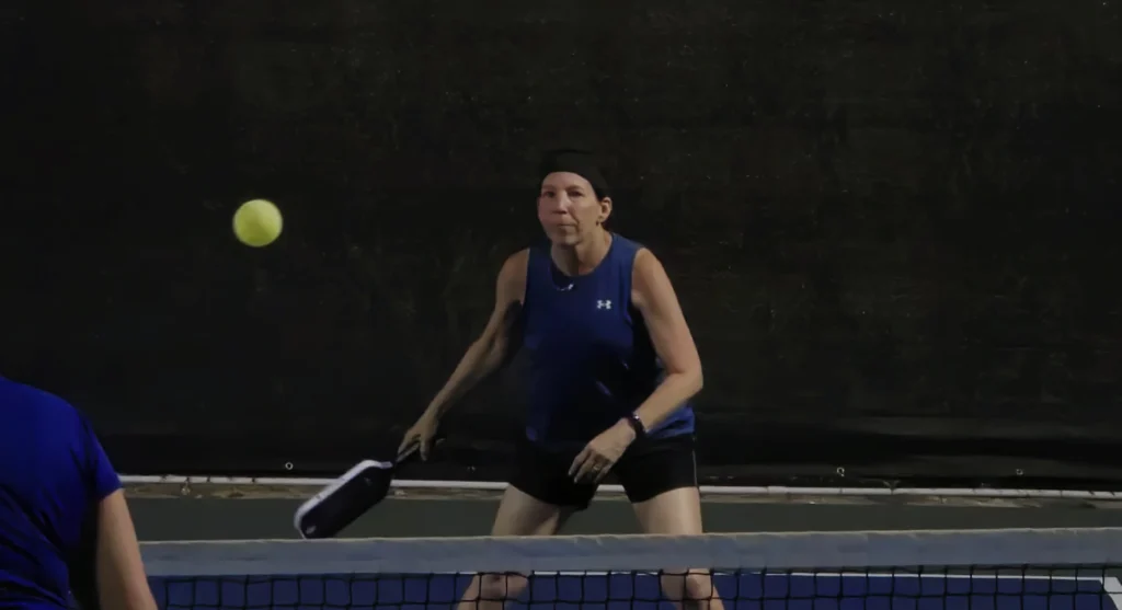 Janel preparing for a backhand volley at the kitchen line while testing the Cyclotron Maks 001 paddle