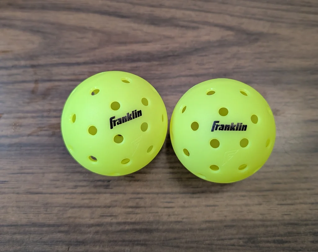 Two bright yellow Franklin X-44 pickleballs before testing.